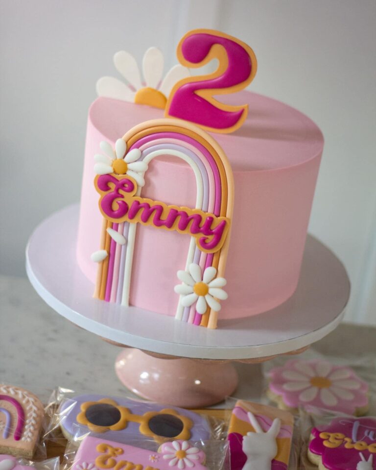 Emmy's 2 Groovy Cake and Cookies: An 8" cake, serving up to 24 portions, featuring a delightful pink and groovy theme. The cake is adorned with daisies and a handmade cake topper, showcasing intricate buttercream designs for a whimsical and delicious celebration